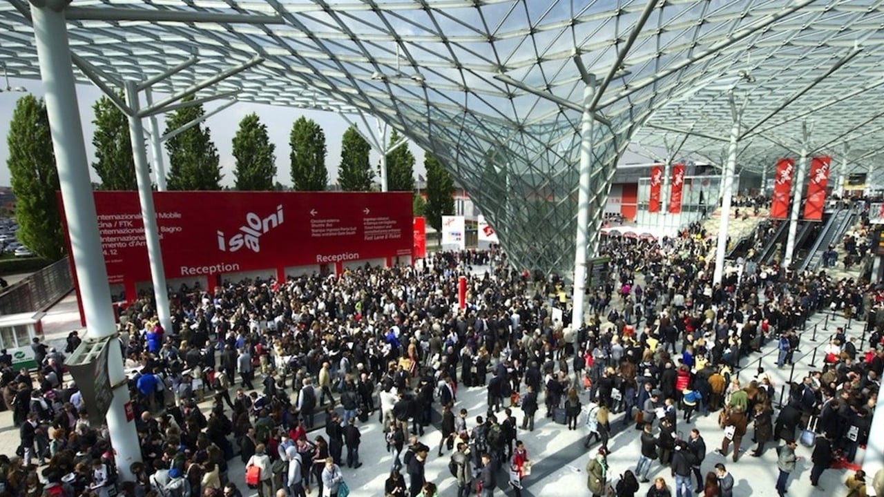 Crowd under a glass lattice canopy at a trade fair entrance