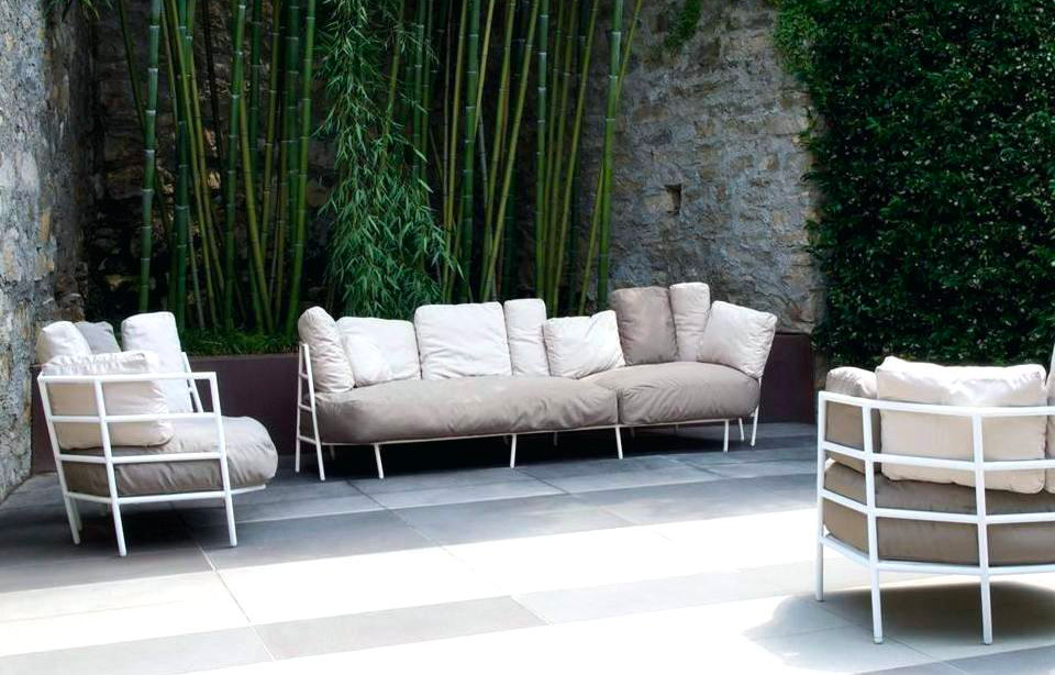 Outdoor lounge seating with white and beige cushions among bamboo and greenery