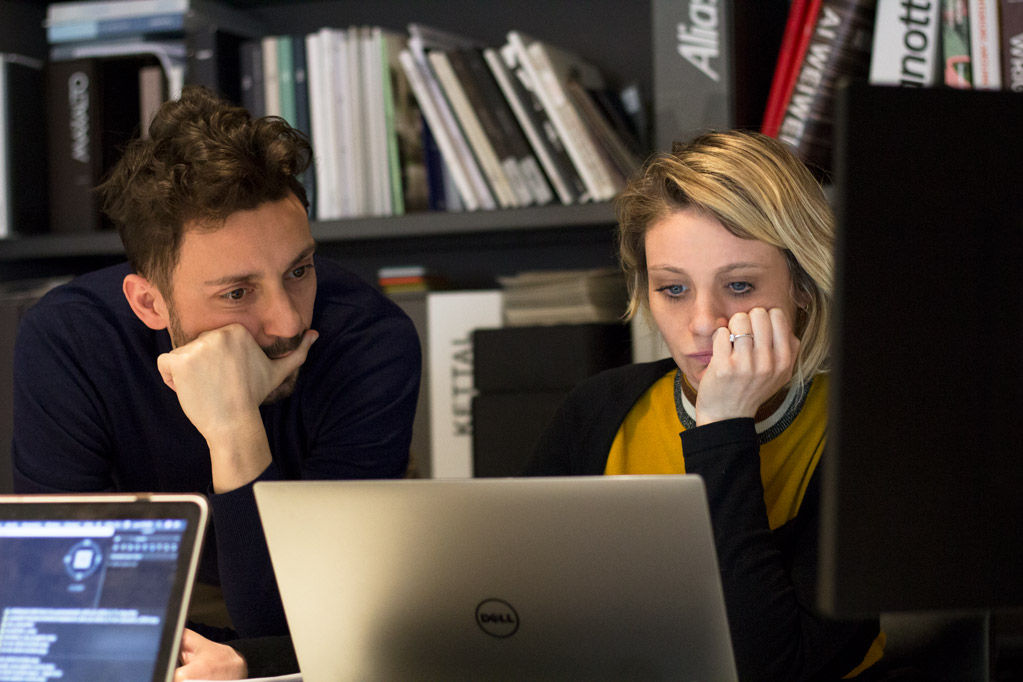 Two designers reviewing work together at a laptop in the studio