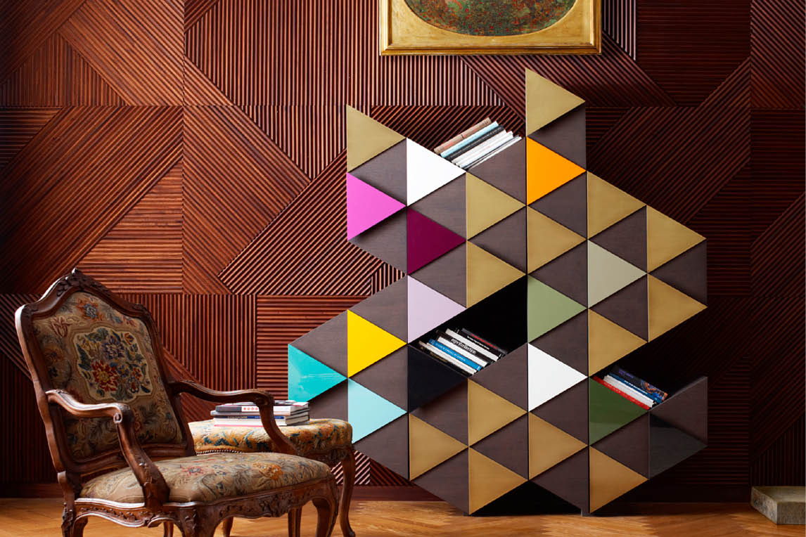 Cabinet with multicoloured triangular doors next to an antique armchair