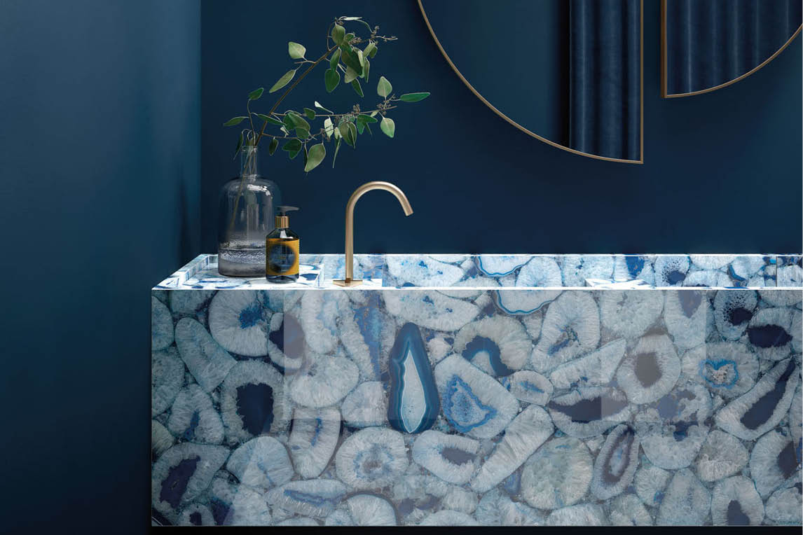 Blue agate wash basin with a brass tap against a dark blue wall