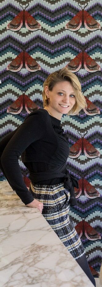 Woman posing against patterned wallpaper