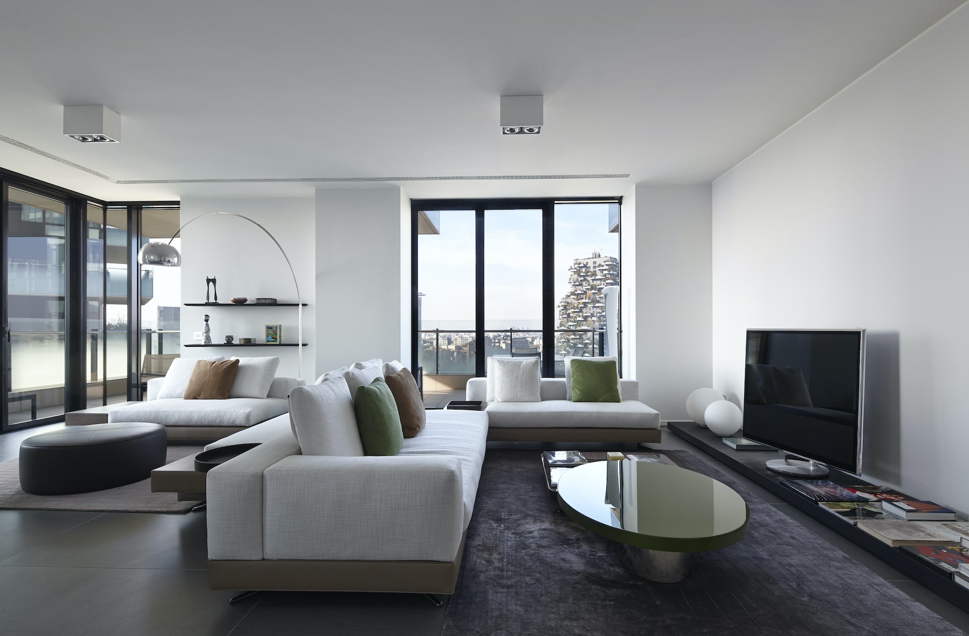 Modern living room with white sofas, green cushions and floor-to-ceiling windows