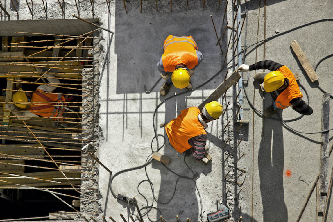 Construction workers in hard hats on a building site, seen from above
