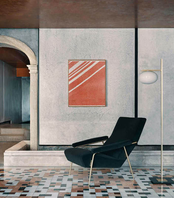 Dark green armchair and floor lamp in a room with a terrazzo floor and a red abstract painting
