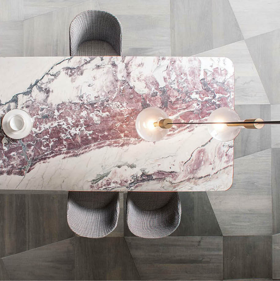 Marble dining table with grey chairs and a brass pendant lamp, seen from above