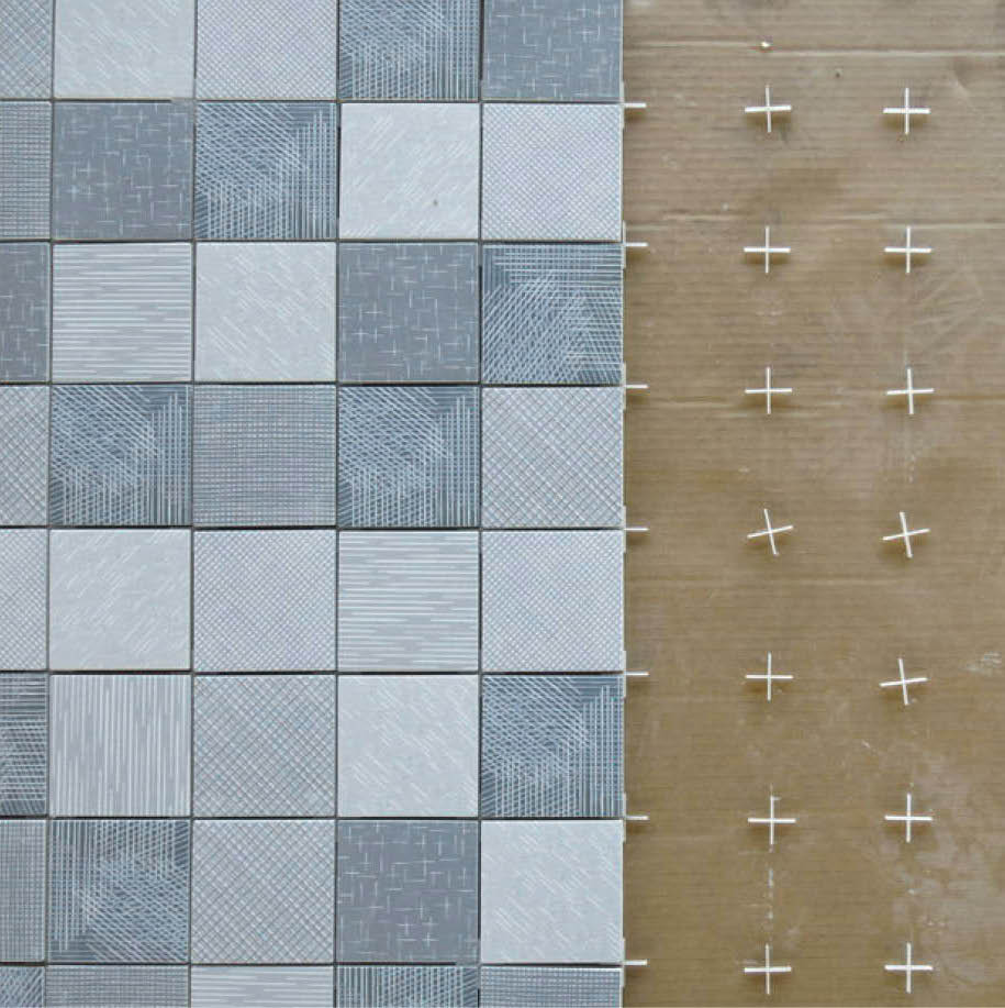 Grey textured floor tiles being laid with spacers