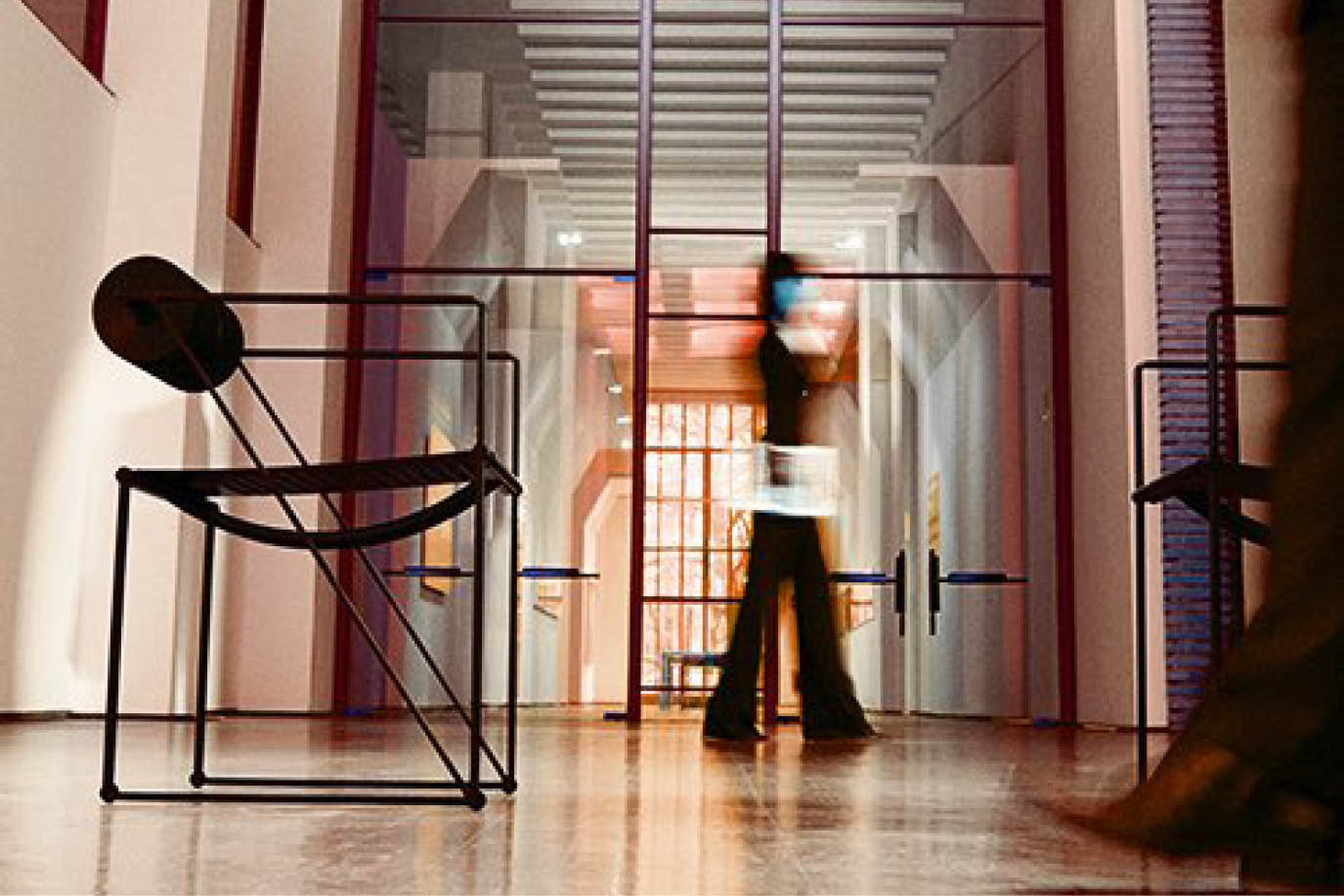 Person walking through a showroom past a black metal chair