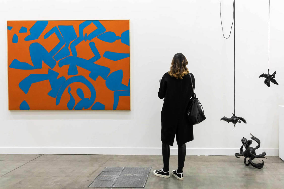 Visitor looking at an orange and blue painting in an art gallery