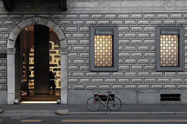 Rimadesio storefront with illuminated display windows on a stone facade at night