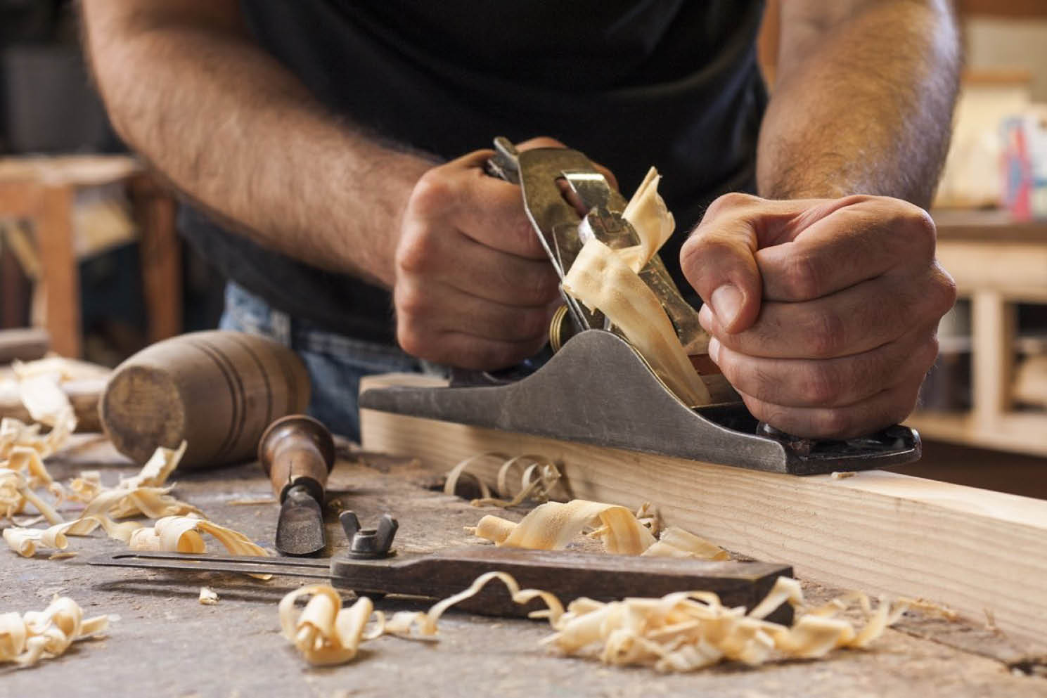 Carpenter planing a wooden board in a workshop