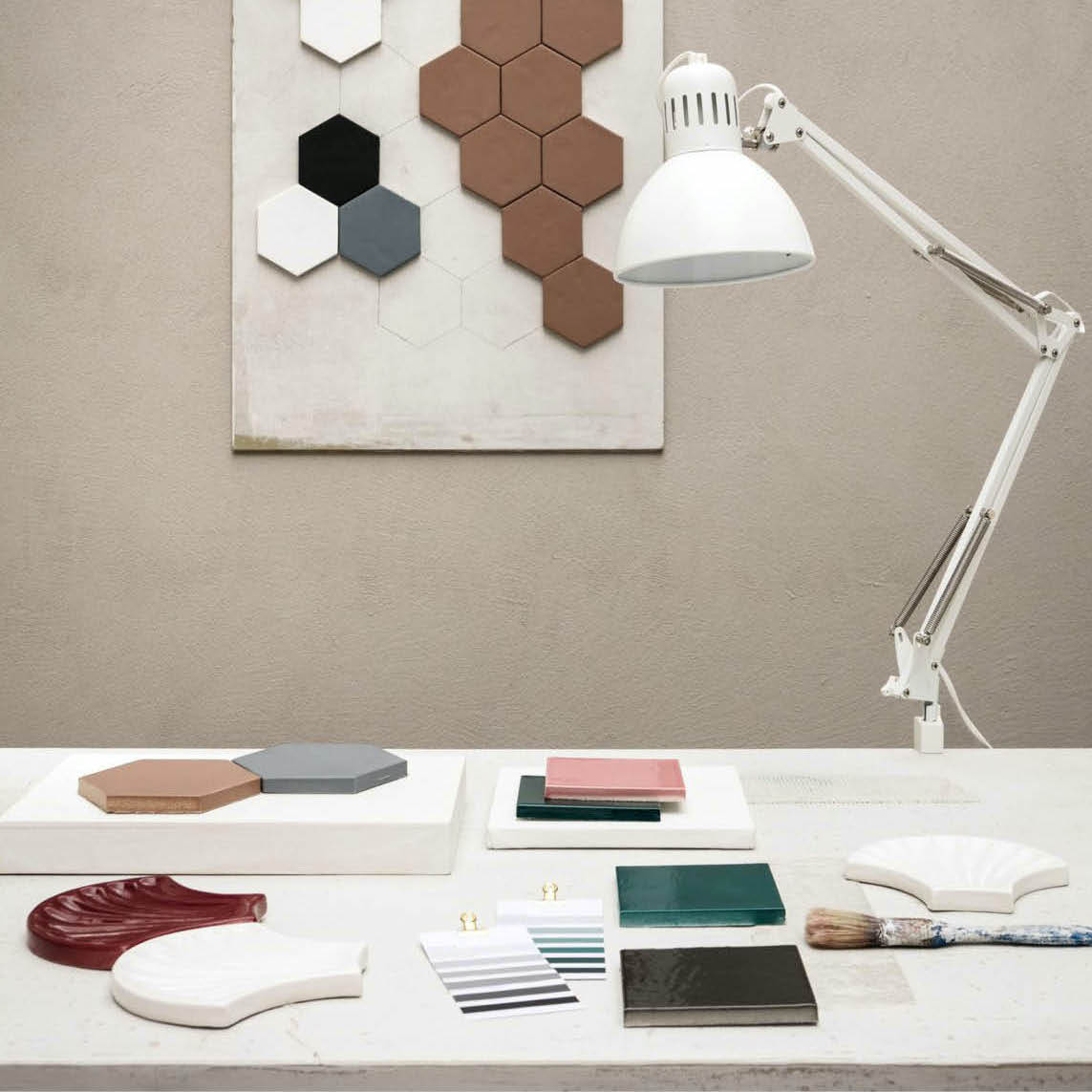 Desk with ceramic tile samples, colour swatches and a white lamp