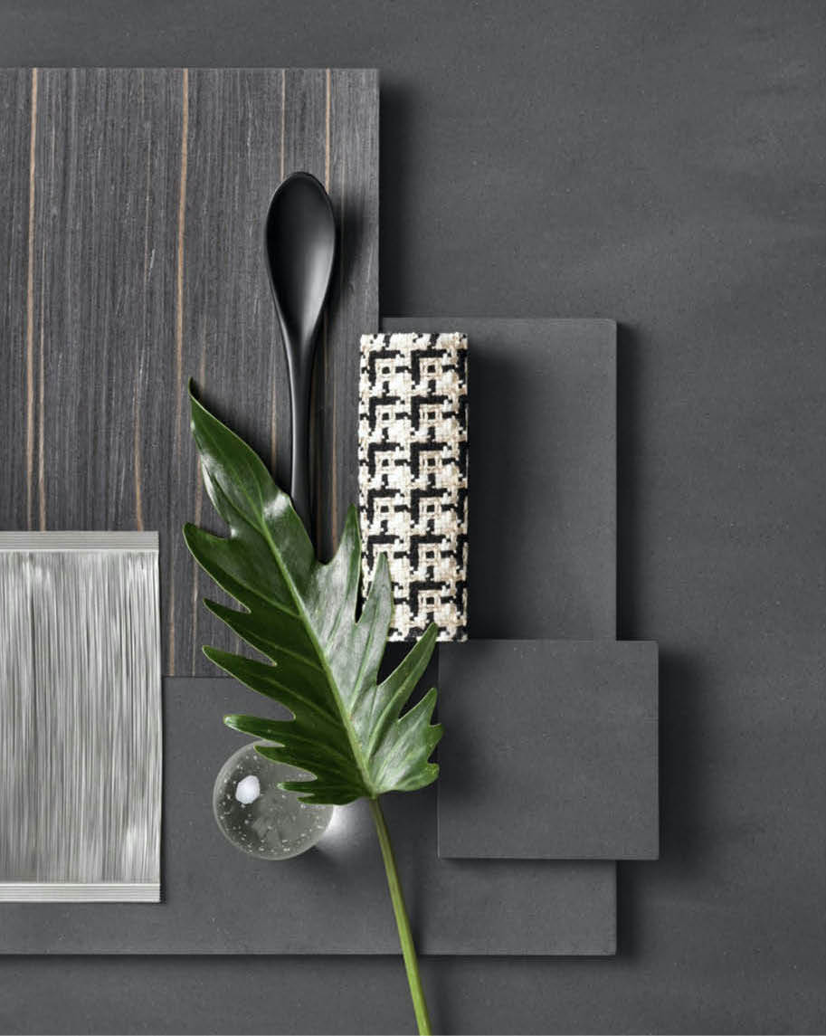 Moodboard with dark wood, brushed metal and houndstooth fabric samples and a tropical leaf