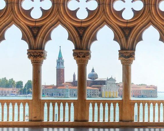 View through Gothic arched columns of a domed church across the water in Venice