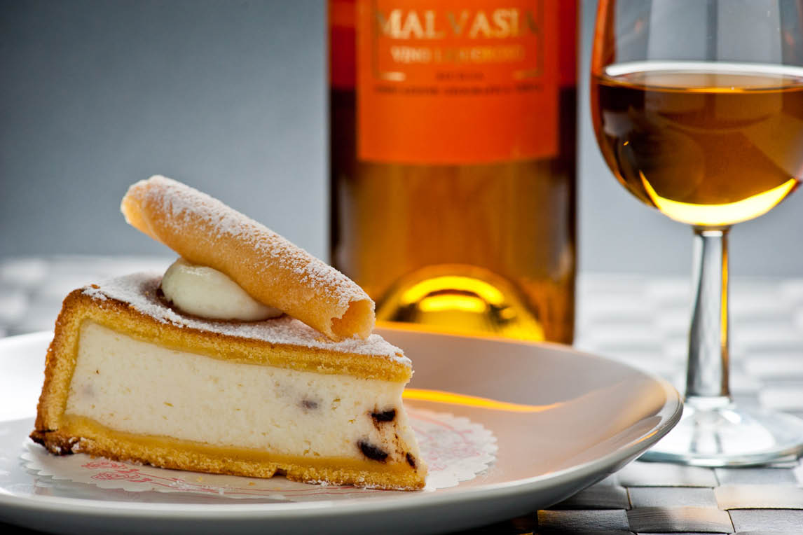 Slice of cheesecake with a biscuit and a glass of dessert wine
