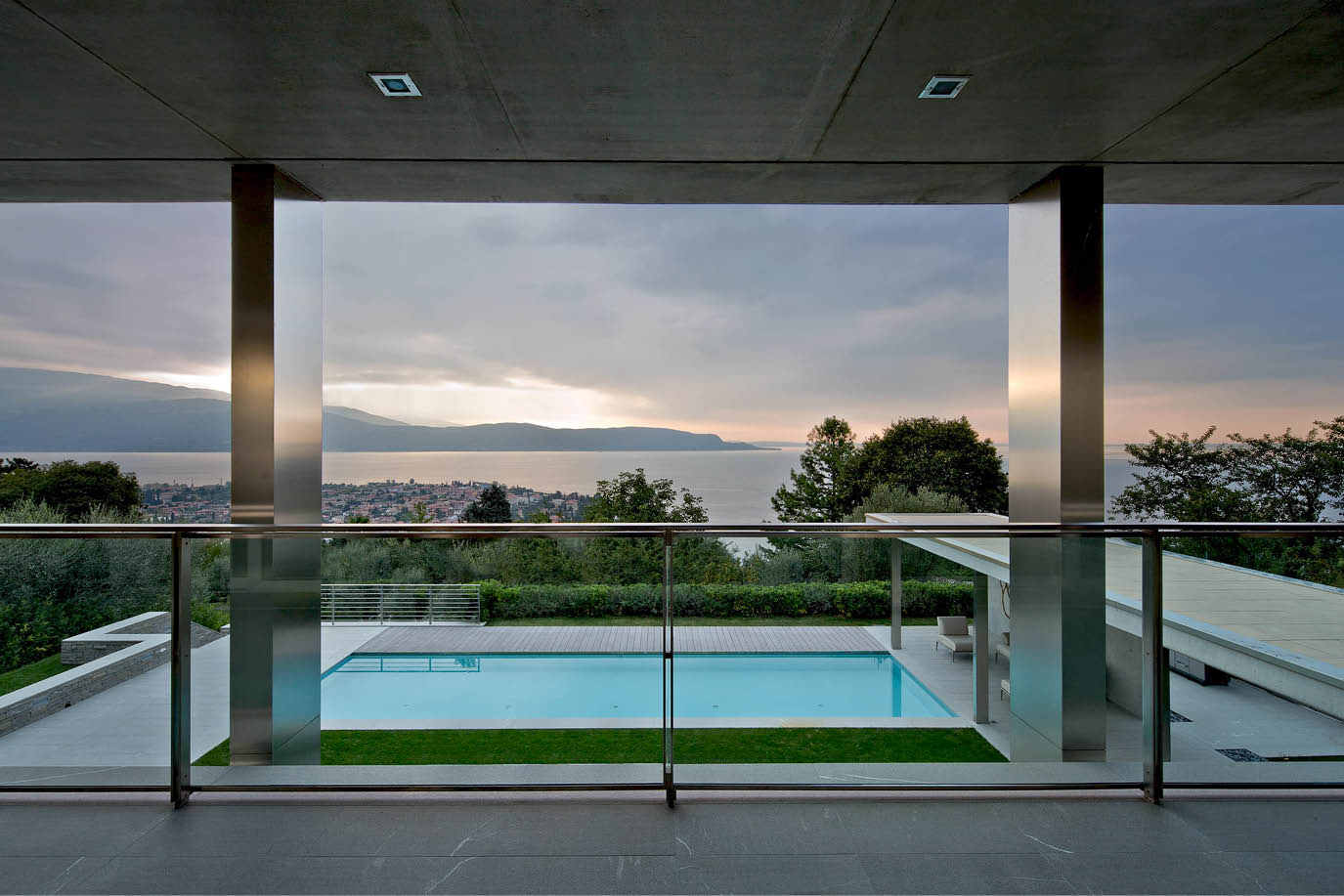 Covered terrace overlooking a pool and a lake at sunset