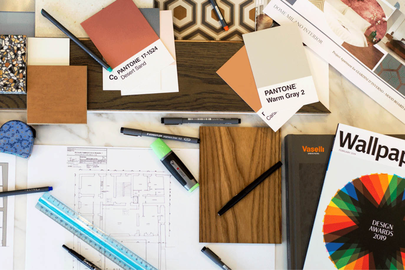 Floor plan with Pantone swatches, wood and tile samples and pens on a marble desk