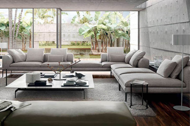 L-shaped grey sofas around a coffee table facing a garden with tropical palms