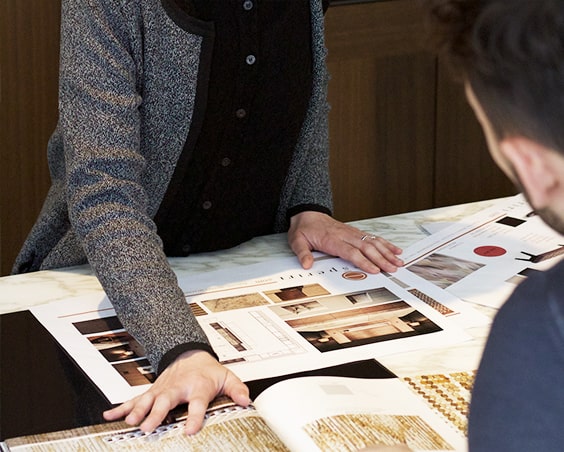 Two people reviewing design catalogs and mood boards on a table