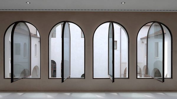 Row of arched steel-framed windows opened onto a museum courtyard