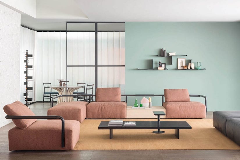 Living room with pink modular sofas, a low black coffee table and a mint green wall