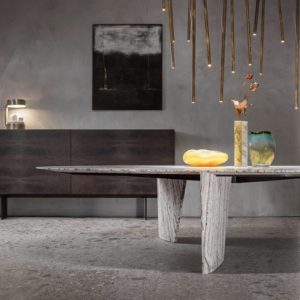 Dining table with a stone base beneath hanging pendant lights and a dark wood sideboard