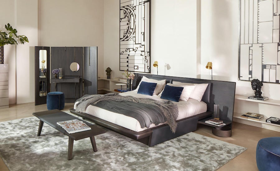 Bedroom with a dark grey upholstered bed, navy and grey pillows and a wooden bench at the foot of the bed